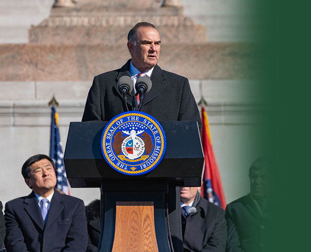 Governor Mike Kehoe speaking at the podium during his Inauguration
